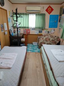 a room with two beds and a table and a desk at Cottage Ureshino in Saga