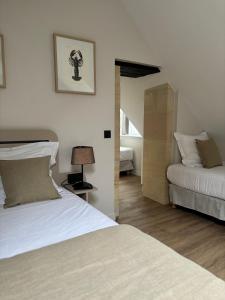 a bedroom with two beds and a lamp in it at Hôtel De La Marine in Arromanches-les-Bains