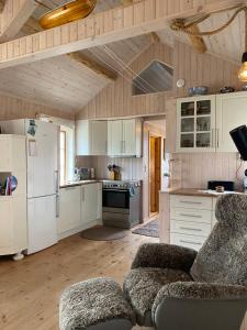a large kitchen with white appliances and wooden ceilings at Unstad cabin with seaview in Unstad