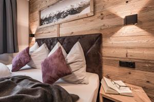 a bedroom with a bed with pillows and a wooden wall at Villa Romantica Appartement in Mayrhofen