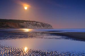 una luna che sorge su una spiaggia di notte di Bay Reach a Sandown