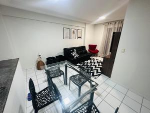 uma sala de estar com uma mesa de vidro e cadeiras em Apartamento 2 quartos na Jatiúca em Maceió