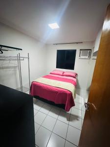um pequeno quarto com uma cama com um cobertor vermelho em Apartamento 2 quartos na Jatiúca em Maceió
