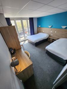 a hotel room with two beds and a desk at Hôtel Le Petit Vatel - Centre ville & Plage in Le Havre