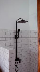 a shower head in a white tiled bathroom at Nebo Apartments Paje in Paje