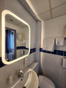 een badkamer met een wastafel, een spiegel en een toilet bij Hôtel Le Petit Vatel - Centre ville & Plage in Le Havre