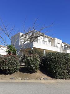 a white building with bushes in front of it at Bel appartement avec piscine- Poggio Mezzana in Poggio-Mezzana