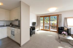 a kitchen and living room with a table and chairs at Ferienwohnungen Hotel Allegra in Zuoz
