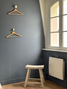 a table and a stool in a room with a window at Hôtel De La Marine in Arromanches-les-Bains