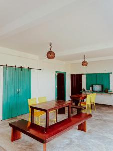 a room with two wooden tables and yellow chairs at CASA VIDASURF in Pipa