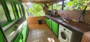 a green kitchen with a sink and a washing machine at La PAPAYERAIE in Le Marin