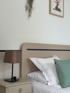 a bed with white pillows and a lamp on a night stand at Hôtel De La Marine in Arromanches-les-Bains