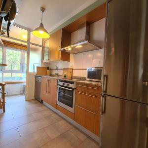 Una cocina con gabinetes de madera y un refrigerador de acero inoxidable. en Playa de Mera, en Mera