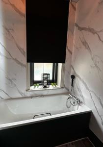 baño con bañera blanca y ventana en Queensmead Hotel en Shanklin