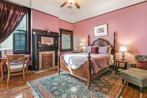 a bedroom with pink walls and a bed and a fireplace at Canal Street Inn in New Orleans