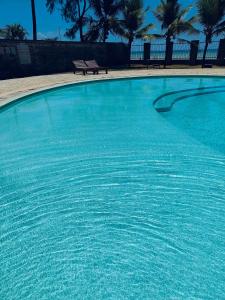 una gran piscina azul con banco y palmeras en Modern Beachfront 3 Bedroom Mombasa near Nyali en Mombasa