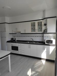 a white kitchen with white cabinets and a sink at Apartamento Area Pequena Ézaro in Ézaro