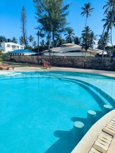 una gran piscina con agua azul y palmeras en Modern Beachfront 3 Bedroom Mombasa near Nyali en Mombasa