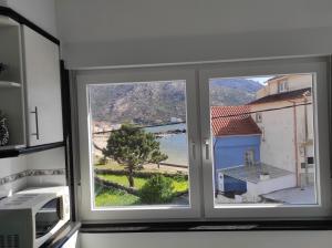 - une fenêtre dans une cuisine avec vue sur un bâtiment dans l'établissement Apartamento Area Pequena Ézaro, à Ézaro