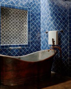uma banheira antiga numa casa de banho com azulejos azuis em Casa de Sierra Nevada, A Belmond Hotel, San Miguel de Allende em San Miguel de Allende