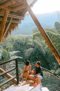 due persone sedute su un ponte sospeso tra le montagne di ATTRAVERSIAMO BAMBOO HOUSE a Manizales