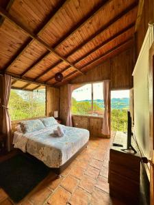 een slaapkamer met een bed in een kamer met ramen bij Refugio Aventura, espectacular cabaña en las montañas de Tabio, Cundinamarca in Tabio