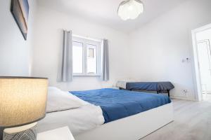 een witte slaapkamer met een blauw bed en een raam bij Appartamento Libeccio a 300m dalla spiaggia in Golfo Aranci