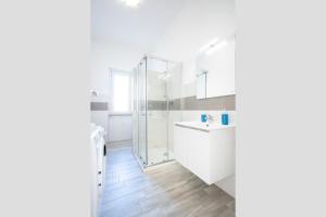 een witte badkamer met douche en wastafel bij Appartamento Libeccio a 300m dalla spiaggia in Golfo Aranci +24 foto's