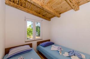 1 dormitorio con 2 camas y ventana en Kuća Neven en Stomorska