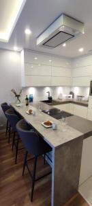 a kitchen with a long island with chairs and a counter at Gold Apartments Penthouse in Rzeszów