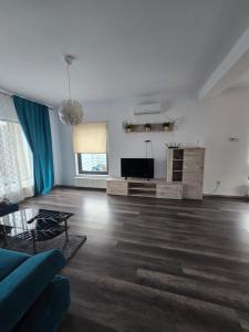 uma sala de estar com um sofá azul e uma televisão de ecrã plano em DA Residence em Otopeni