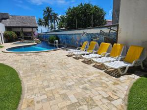 a group of lounge chairs next to a swimming pool at AP Completo Tabatinga in Nísia Floresta