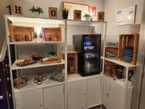 a kitchen with white shelves with food and a refrigerator at Hôtel Le Petit Vatel - Centre ville & Plage in Le Havre