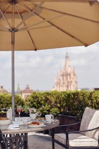 聖米格爾－德阿連德的住宿－Casa de Sierra Nevada, A Belmond Hotel, San Miguel de Allende，餐桌,带食物盘和雨伞