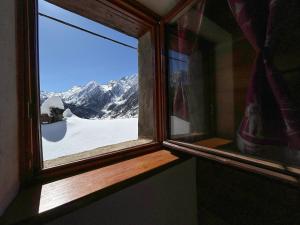 een raam met uitzicht op een met sneeuw bedekte berg bij La casetta in Prali