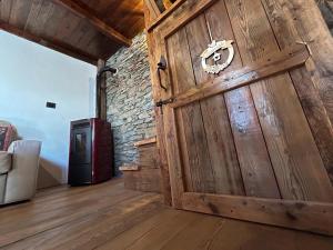 uma grande porta de madeira num quarto com uma parede de tijolos em La casetta em Prali