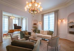 a living room with a chandelier and a piano at LA FOLIE in Forges-les-Eaux