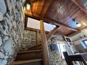 a room with a stone wall and wooden ceilings at La casetta in Prali