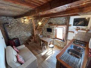 uma sala de estar com um sofá, uma mesa e uma cozinha em La casetta em Prali