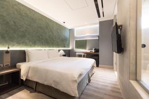 馬公市的住宿－綠的旅店，一间卧室配有一张大床和电视