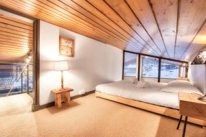 una camera da letto con un letto con soffitto in legno di Le Contemporain - Chalet vue sur le Mont Blanc a Saint-Gervais-les-Bains