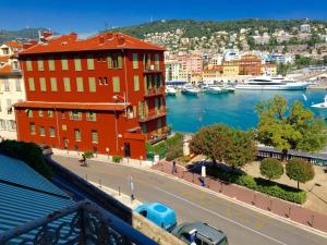 a red building next to a body of water with boats at Résidence Rauba Capeu in Nice