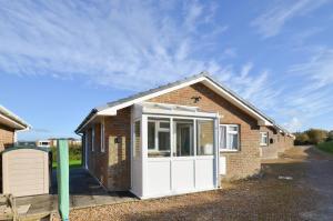 a small brick house with a white door at 2 Brambles Farm Holiday Bungalow in Freshwater