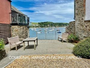 a patio with two benches and a view of a harbor at 4 Bedroom Cottage with panoramic Harbour views in Falmouth