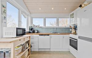 una cocina con armarios blancos, fregadero y ventanas en Cozy Home In Knebel With Sauna, en Knebel