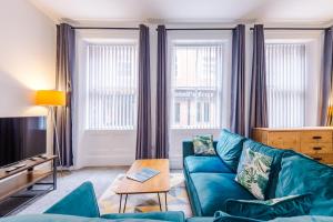 a living room with a blue couch and two windows at The Old Embassy by Guestz in Hull