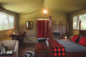 ein Schlafzimmer mit einem Bett in einem Zelt in der Unterkunft Drunken Elephant Mara in Sekenani