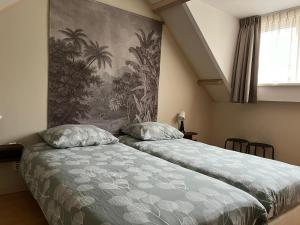 een slaapkamer met 2 bedden en een schilderij aan de muur bij Zomerhuis Beach EnJoy in Egmond aan Zee