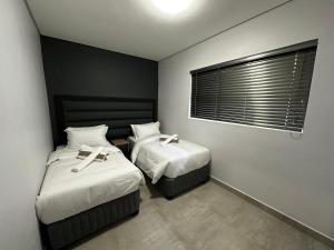 1 dormitorio con 2 camas con sábanas blancas y ventana en 49 on Blackburn, en Durban