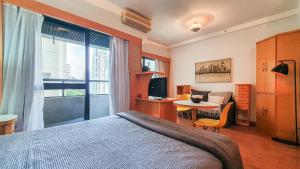1 dormitorio con cama, escritorio y mesa en Flat em Hotel 4 estrelas - Alameda Lorena, en São Paulo